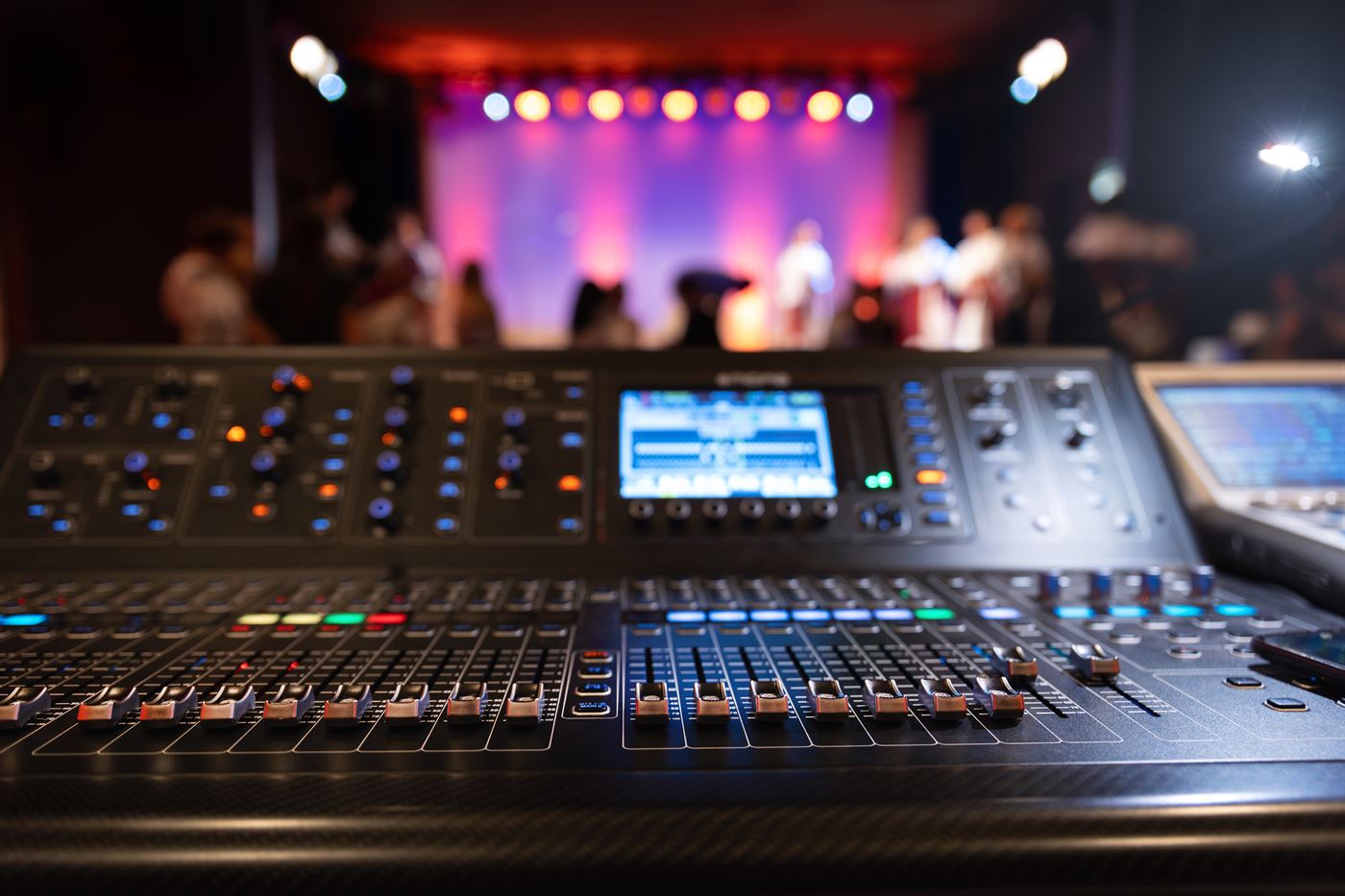 Console de mixage numérique en régie face à une scène éclairée